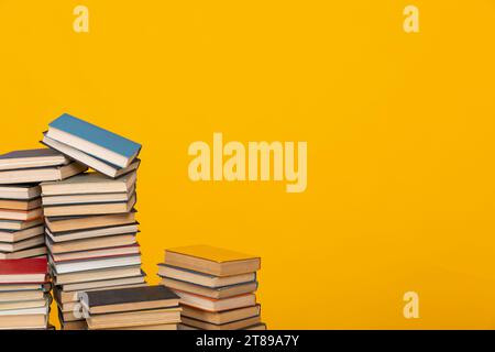 de nombreux livres empilés dans la bibliothèque sur un fond jaune de lecture des connaissances scientifiques Banque D'Images