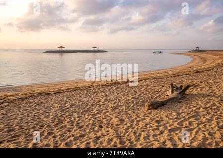 Lever de soleil magique avec des nuages dans le ciel. Ciel spectaculaire sur la plage de Sanur, Denpasar à Bali. Temple dans la mer calme le matin. Paysage tropical photographié Banque D'Images