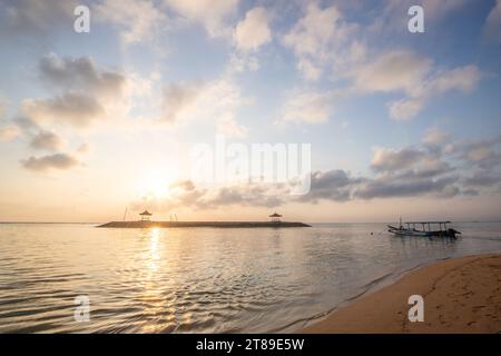 Lever de soleil sur la plage de sable de Sanur. Temple dans l'eau. Bateau de pêche traditionnel, Jukung sur la plage. Foi hindoue à Sanur sur Bali. Île de rêve Banque D'Images