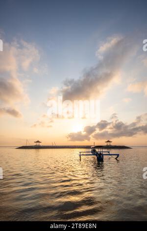 Lever de soleil sur la plage de sable de Sanur. Temple dans l'eau. Bateau de pêche traditionnel, Jukung sur la plage. Foi hindoue à Sanur sur Bali. Île de rêve Banque D'Images