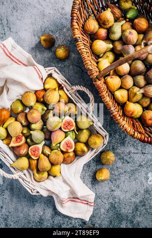 Figues vertes biologiques fraîchement cueillies dans un panier sur fond gris Banque D'Images