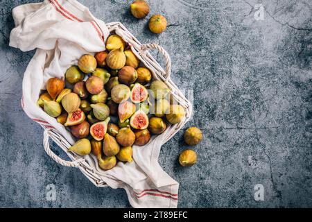 Figues vertes biologiques fraîchement cueillies dans un panier sur fond gris Banque D'Images