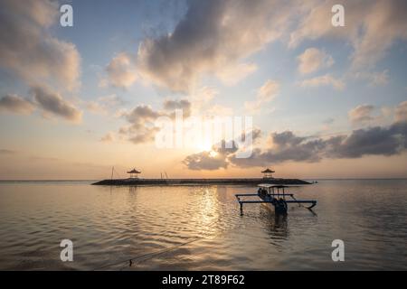 Lever de soleil sur la plage de sable de Sanur. Temple dans l'eau. Bateau de pêche traditionnel, Jukung sur la plage. Foi hindoue à Sanur sur Bali. Île de rêve Banque D'Images