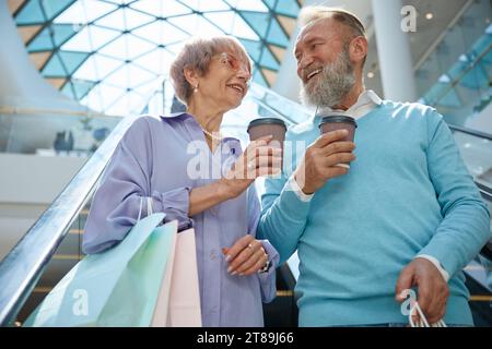 Couple de seniors descendant l'escalator du centre commercial Banque D'Images