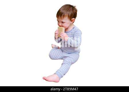 Bébé en bas âge joue avec des produits chimiques ménagers et détergent du placard, isolé sur fond blanc. Enfant garçon avec bouteille de détergent dans la vie à la maison Banque D'Images