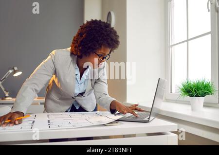 Jeune femme designer d'intérieur regardant le plan d'étage de la nouvelle maison sur l'écran de moniteur d'ordinateur portable. Banque D'Images