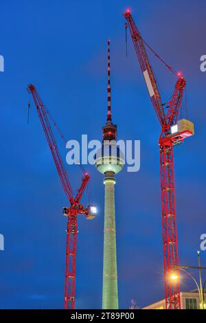 La célèbre tour de télévision de Berlin la nuit avec deux grues de construction rouges Banque D'Images