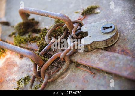 un gros plan sur une trappe en métal attachée avec une chaîne et un cadenas ancien avec clés / un gros plan sur une trappe en métal fermée par une chaine et un Banque D'Images