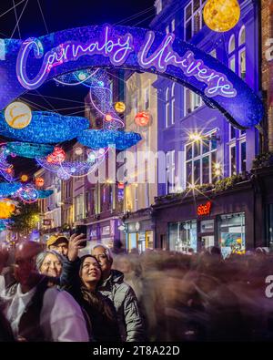 Un touriste prend un selfie sur le thème de Noël de Carnaby Street, « Carnaby Universe » la nuit à Londres. Banque D'Images