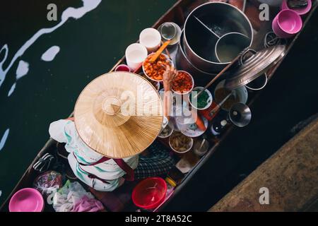 Focalisation sélective sur le chapeau traditionnel du vendeur sur le bateau sur le marché flottant. Femme prépare de la nourriture sur l'eau à Damnoen Saduak près de Bangkok, Thaïlande. Banque D'Images