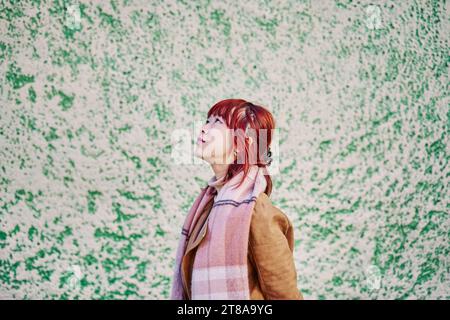 Femme chinoise aux cheveux rouges regardant le ciel sur fond neutre avec Copy Space Banque D'Images