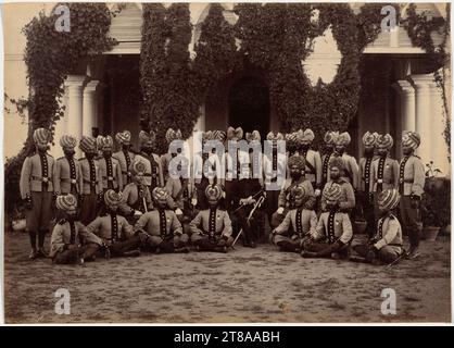 Dans les portraits d'état et militaires, les personnes assises sur des chaises et au milieu sont généralement du rang le plus élevé. Au milieu de ces soldats indiens se trouve un officier britannique solitaire. Le bataillon Bhopal avait combattu seulement six ans plus tôt lors de la deuxième guerre anglo-afghane, aidant à garder l’Afghanistan comme tampon favorable aux Britanniques contre le désir de la Russie de s’étendre en Inde. Ce détachement comprend un certain nombre de Sikhs, identifiables par leurs barbes et turbans soigneusement taillés qui couvrent leurs oreilles. Les membres de ce groupe religieux ont été avidement recrutés par l'armée indienne britannique en raison de leur férocité réputée et Banque D'Images