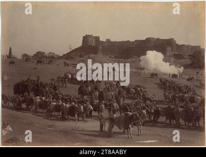 Les exercices impliquant des batteries d'éléphants, exotiques aux yeux des Européens, attiraient les spectateurs ; les photographies d'entre eux étaient d'excellents souvenirs de ces forces militaires employées par l'armée indienne britannique. Les éléphants avaient été employés dans la guerre en Inde depuis au moins les années 500 av. J.-C., mais avec l'avènement de l'artillerie lourde, leur fonction est passée de l'attaque à l'appui. Ils transportaient de grosses armes et des fournitures et travaillaient dans l'exploitation forestière et la construction. Il a fallu beaucoup de bétail pour tirer une charge qui pouvait être manipulée par deux éléphants. Fort de Jhansi et batterie d'éléphants, 1886. Raja Deen Dayal (Indien, 1844-1905). Banque D'Images