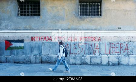Gênes, Italie - 18 novembre 2023 : message graffiti de protestation pro-Palestine sur un mur à Gênes, Italie alors qu'une personne passe devant Banque D'Images
