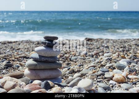 Pyramide de galets de mer sur une plage de sable ensoleillé. Le concept de vie Banque D'Images