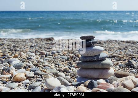 Pyramide de galets de mer sur une plage de sable ensoleillé. Le concept de vie Banque D'Images