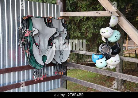 Équipement d'escalade - casques colorés et gilets de sécurité accrochés à une planche dans un parc de corde en gros plan Banque D'Images