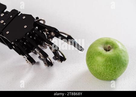 Main de vrai robot avec pomme verte. Concept de développement d'intelligence artificielle et d'automatisation de processus robotisés. Banque D'Images