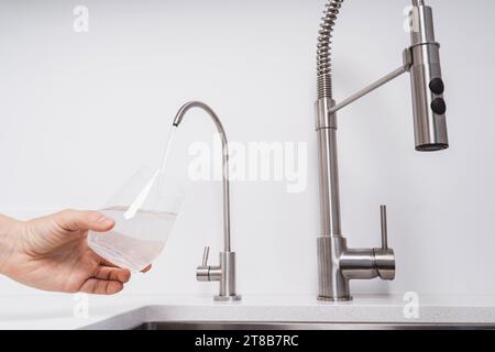 Femme obtenir l'eau filtrée du robinet inoxydable dans un verre Banque D'Images