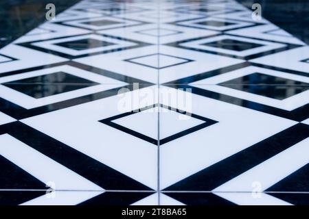 Constructeurs posant des carreaux, de nouveaux carreaux noirs et blancs sur le sol dans la cuisine. Concept de rénovation. Photo de haute qualité Banque D'Images