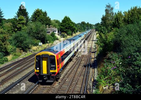 Un train du South Western Railway London Waterloo à Exeter St Davids est vu en passant devant le Railway Cottages à Worting Junction à l'ouest de Basingstoke. Banque D'Images