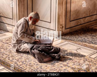 DELHI, INDE - 20 DÉCEMBRE 2022 : un homme non identifié lit le Coran dans la mosquée Jama Masjid dans le vieux Delhi. Banque D'Images