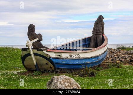 L 'Repus" une pêche restauré par le coble plage à Skinningrove, North Yorkshire, England, UK avec deux sculptures en bois des pêcheurs Banque D'Images