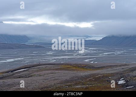 Glacier lointain couvant dans le brouillard au-dessus de sa vallée glaciaire à Lomfjorden dans les îles du Svalbard Banque D'Images