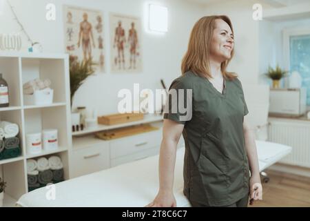 Le temps des soins de santé. femme thérapeute de massage souriante dans l'armoire de massage. Banque D'Images