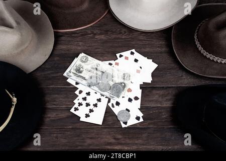 Vieux chapeaux de l'Ouest avec carte à jouer avec des papiers argent et pièces d'argent sur la table. Vue de dessus. Banque D'Images