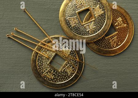 Aiguilles d'acupuncture et pièces chinoises antiques sur table en bois gris, pose plate Banque D'Images