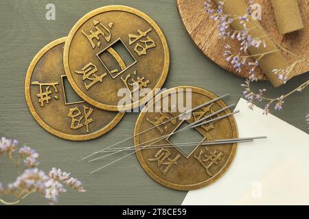 Aiguilles d'acupuncture, bâtons de moxa et pièces chinoises antiques sur table en bois gris, pose à plat Banque D'Images