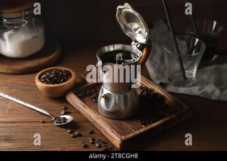 Café infusé dans un pot de moka et des grains sur une table en bois Banque D'Images