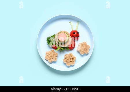 Assiette avec le petit déjeuner drôle pour enfants en forme d'escargot sur fond bleu Banque D'Images