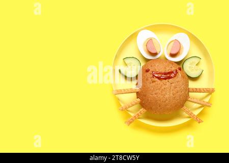 Assiette avec le petit déjeuner drôle des enfants en forme de crabe sur fond jaune Banque D'Images