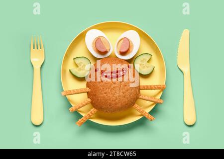 Assiette avec le petit déjeuner drôle des enfants en forme de crabe sur fond vert Banque D'Images