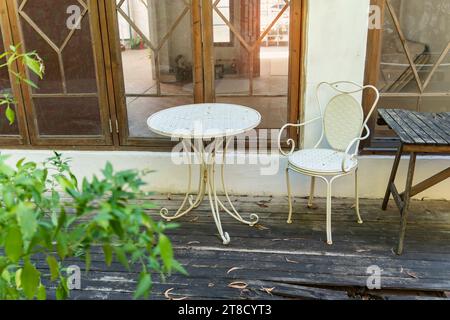 patio avec chaises et tables à l'ombre parmi les plantes et les fleurs près de la fenêtre Banque D'Images