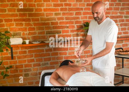 physiothérapeute effectuer une thérapie de ventouse avec massage d'aspiration à la femme adulte hispanique en forme dans le lit thérapeutique pour le soulagement du stress Banque D'Images