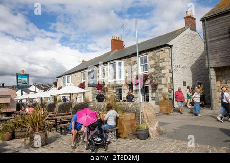 Les gens assis à l'extérieur du pub anglais, le Harbour Inn à Porthleven Cornwall, jour ensoleillé d'automne 2023, Angleterre, Royaume-Uni Banque D'Images