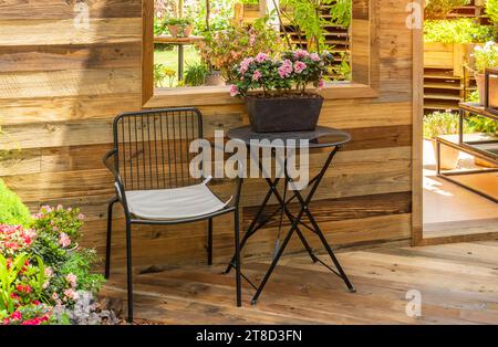 patio avec chaises et tables à l'ombre parmi les plantes et les fleurs près de la fenêtre Banque D'Images