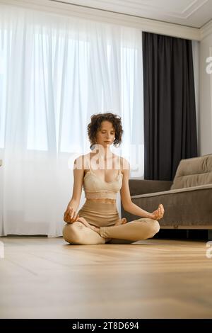 La femme méditative est assise en position lotus à la maison Banque D'Images