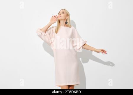 Jolie femme blonde dans la robe de gaine courte regarde vers le haut Banque D'Images