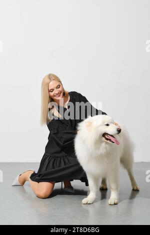 Heureuse femme blonde jouant avec son chien samoyed Banque D'Images