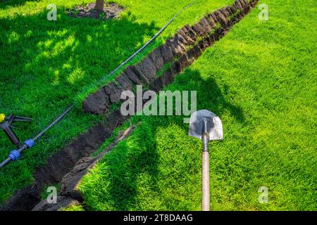 Auto-installation de l'irrigation avec un arroseur rétractable dans la pelouse finie. Pose de conduites d'eau avec des pulvérisateurs sous la pelouse pour l'irrigation. Banque D'Images