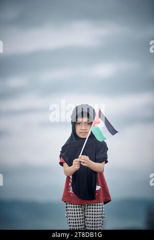 Mignonne petite fille agitant le drapeau de Palestine envoie un message puissant de soutien et d'empathie au monde Banque D'Images