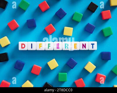 Différence, diversité dans le concept d'éducation.. Cubes colorés sur fond bleu avec le mot différent. Banque D'Images