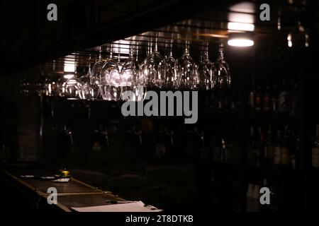 verres suspendus sur le comptoir de bar sur un fond sombre Banque D'Images