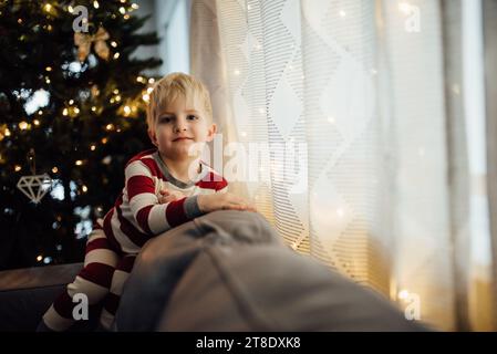 Petit garçon portant pyjama de noël sourit à la caméra devant un Banque D'Images