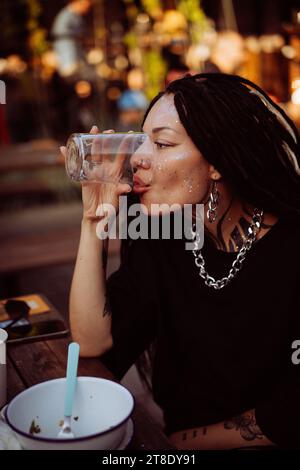 Une jeune femme boit dans un verre dans un café. Banque D'Images