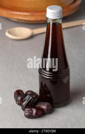 Bouteille en verre avec vinaigre de dattes et dattes séchées devant sur la table Banque D'Images